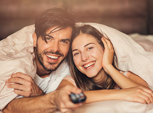Une isolation phonique pour plus de plaisir en home cinéma Un couple apprécie de visionner un film dans leur salle de home cinéma grâce à l’isolation phonique.