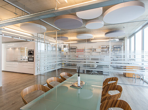 Des salles de réunion avec des séparations en verre et des absorbeurs de bruit ronds aixFOAM Un bureau avec des absorbeurs de bruit rond pour améliorer l’acoustique.