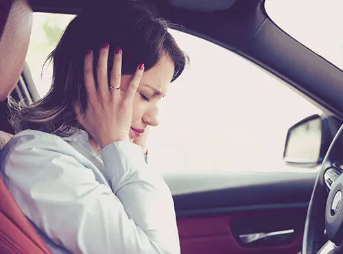 Une femme essaie de se protéger du bruit dans la voiture.