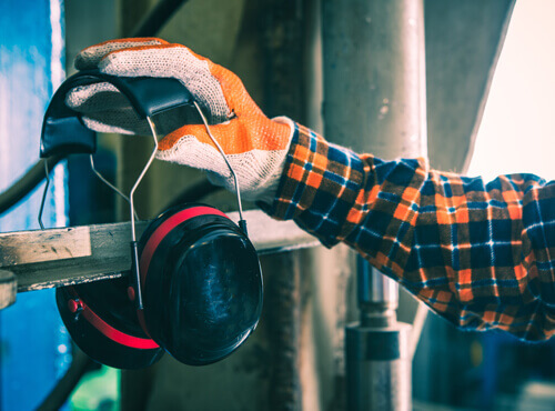 Protection auditive et isolation acoustique dans l’industrie Un travailleur s’équipe d’une protection auditive pour se protéger d’une machine bruyante.