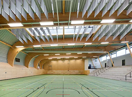 Les absorbeurs de bruit flottants sous le plafond d’une salle de sport réduisent le niveau de bruit et la réverbération.