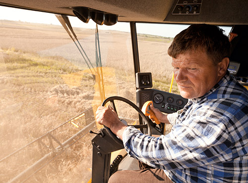 Insonorisation des machines agricoles et forestières Moins de bruit dans l’agriculture – un travailleur conduit une moissonneuse-batteuse insonorisée.