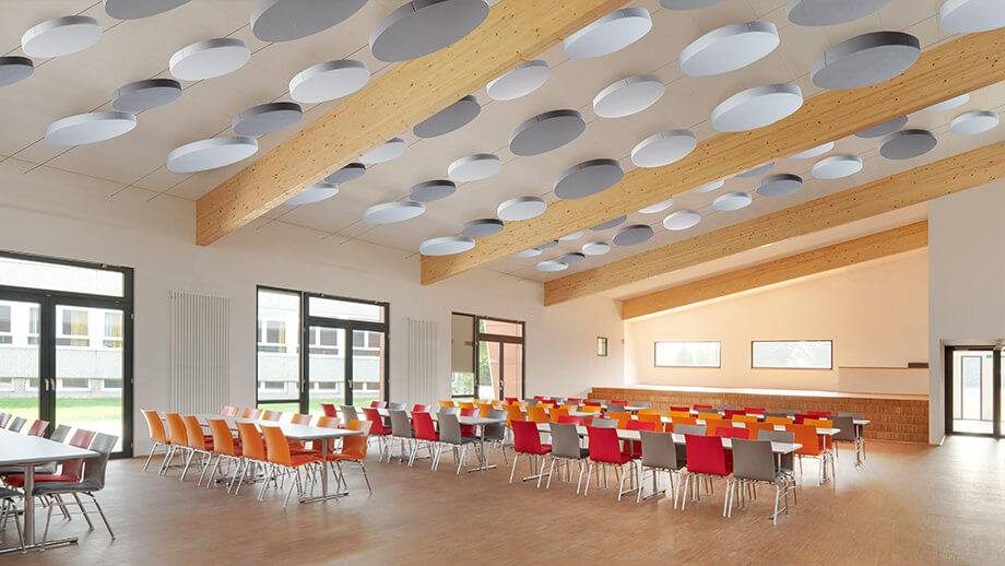 Des voiles acoustiques ronds au plafond d'une cafétéria améliorent l'acoustique.