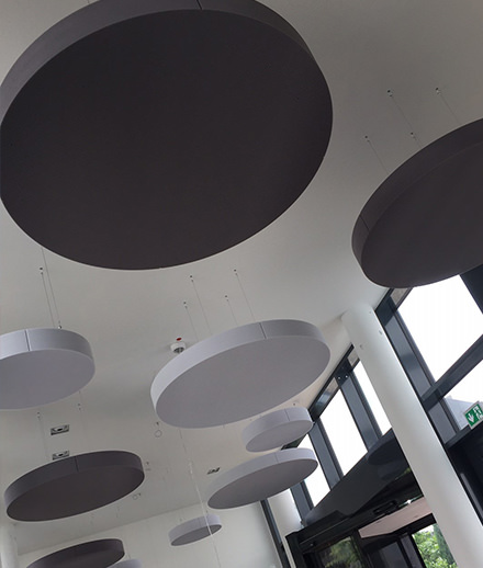 Des voiles acoustiques ronds au plafond d'une salle à manger réduisent le bruit.